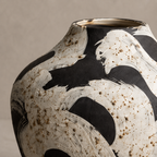 Ceramic vase with black and white abstract design on a beige background