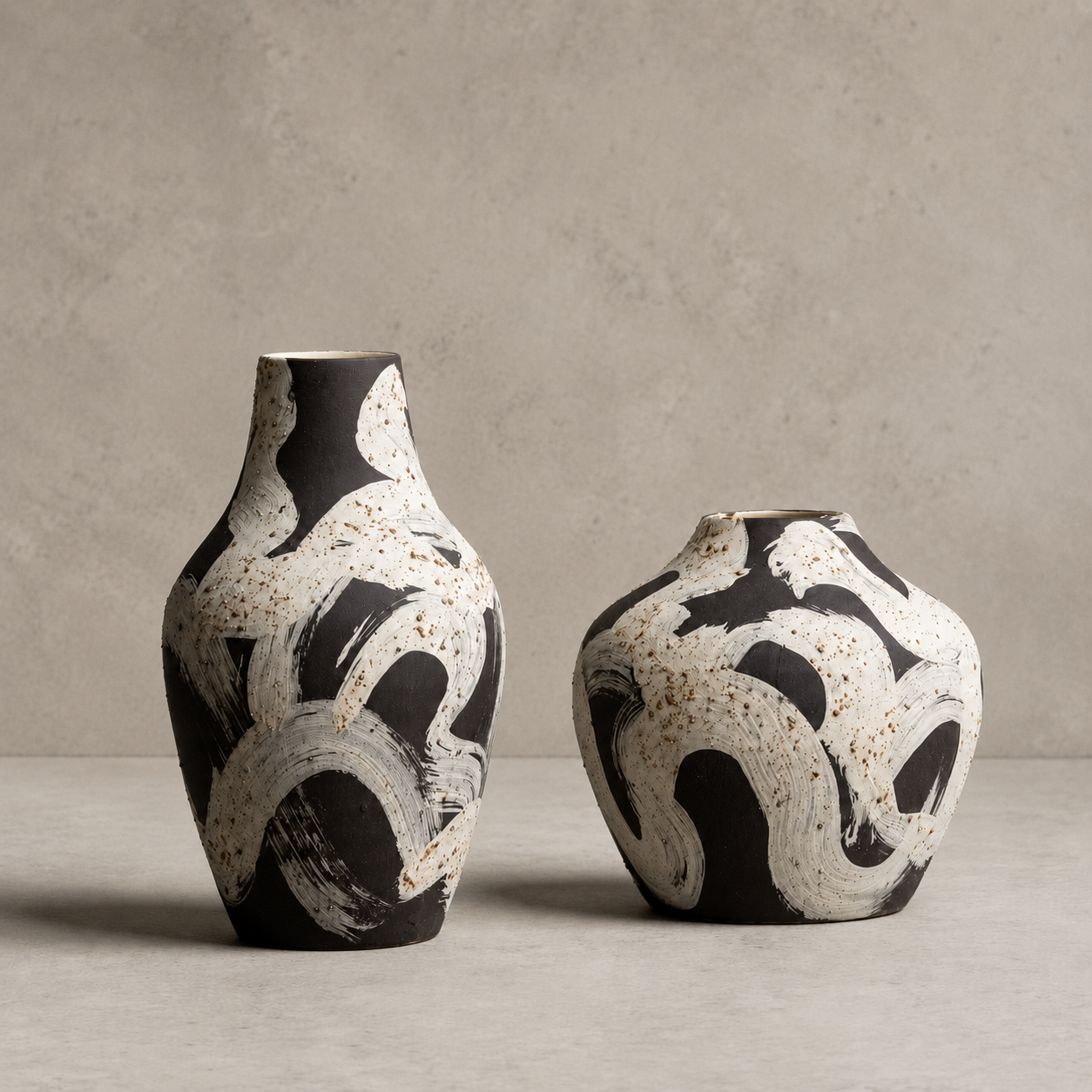 Two ceramic vases with black and white abstract patterns on a neutral background