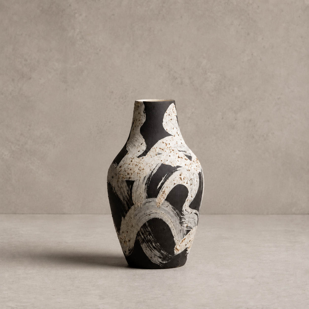 Black and white abstract-patterned vase on a gray surface with a neutral background