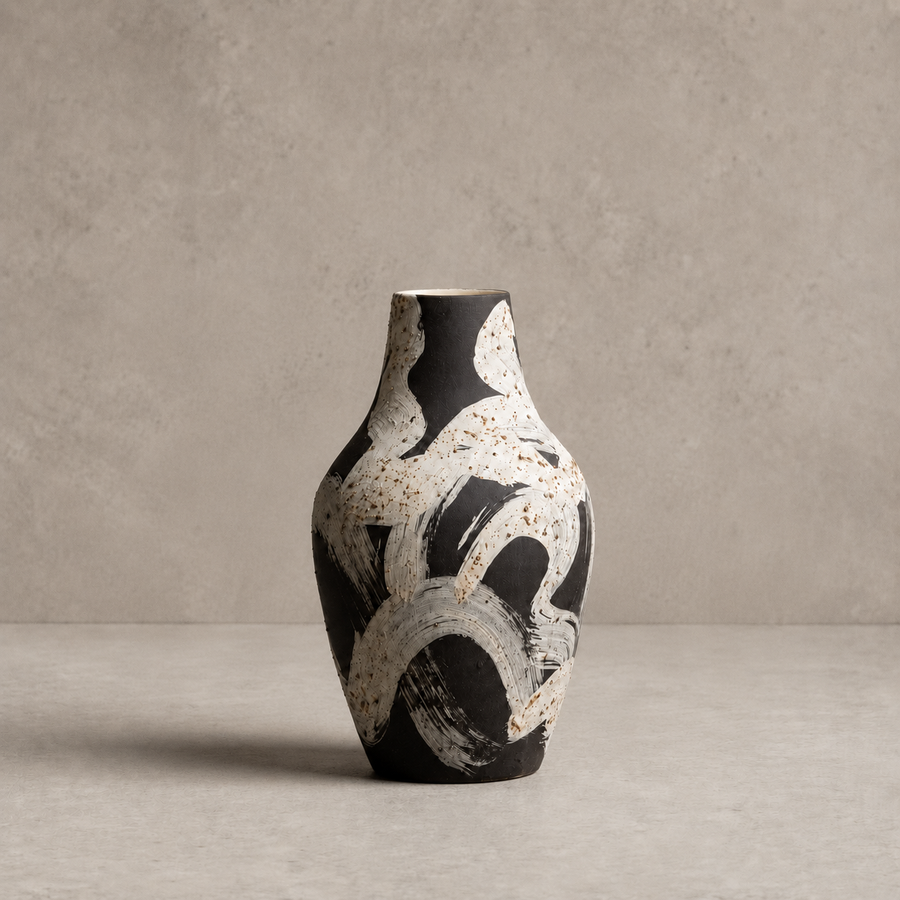 Black and white abstract-patterned vase on a gray surface with a neutral background