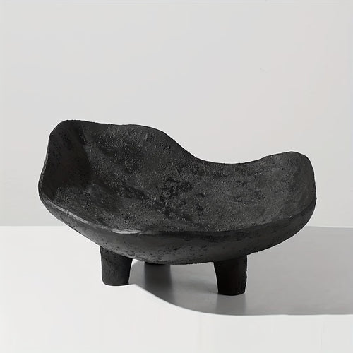 Black stone bowl with three legs on a light gray background
